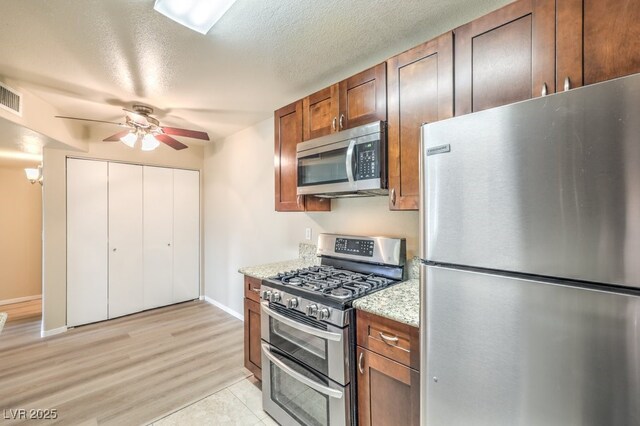 2120 Ramrod Ave Unit 2216, Henderson, NV 89014 - kitchen featuring baseboards, light wood-style flooring, a ceiling fan, brown cabinetry, and stainless steel appliances