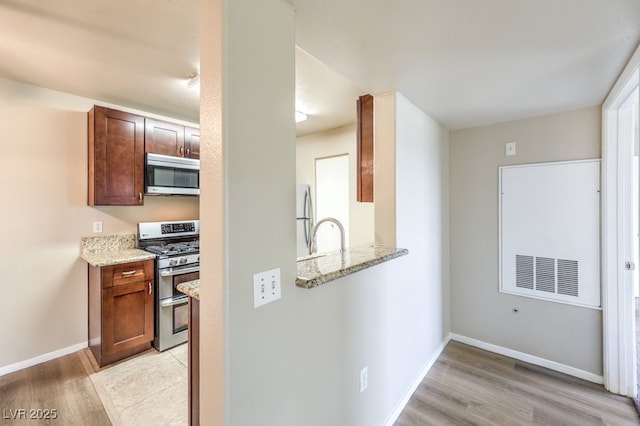 2120 Ramrod Ave Unit 2216, Henderson, NV 89014 - kitchen with light stone countertops, light wood-style floors, baseboards, and appliances with stainless steel finishes