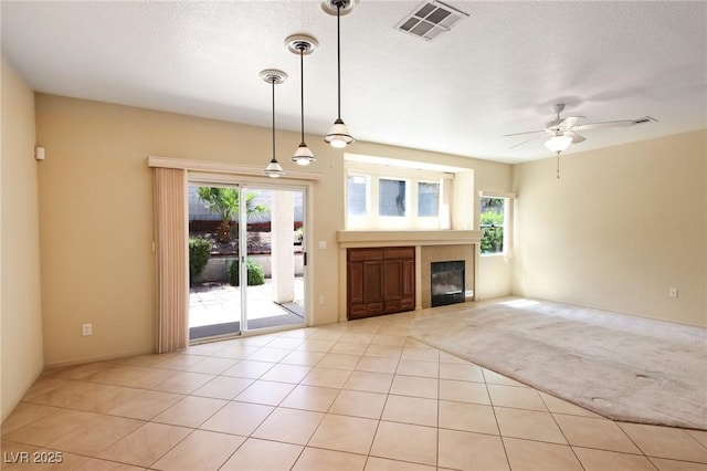 3029 Paseo Hills Way, Henderson, NV 89052 - unfurnished living room featuring plenty of natural light, a ceiling fan, a glass covered fireplace, light tile patterned floors, and a textured ceiling