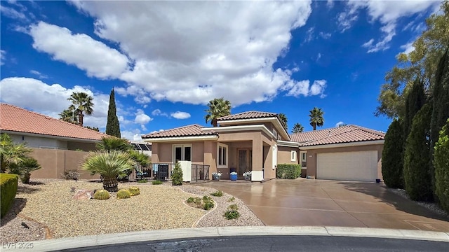 mediterranean / spanish-style house with stucco siding, a garage, fence, a tiled roof, and concrete driveway