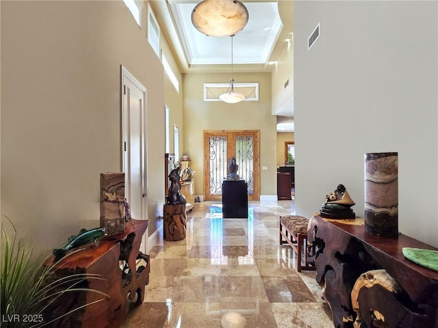 entrance foyer featuring a tray ceiling, ornamental molding, a towering ceiling, marble finish flooring, and baseboards
