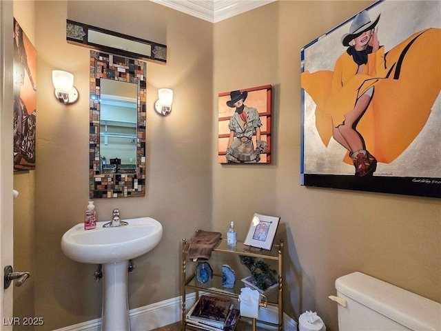 bathroom featuring ornamental molding, toilet, and baseboards