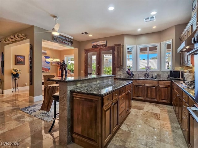 kitchen with a kitchen bar, decorative backsplash, a sink, stainless steel appliances, and a center island