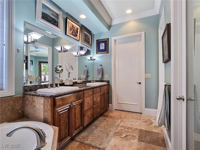 bathroom with crown molding, stone finish flooring, double vanity, a ceiling fan, and a tub to relax in