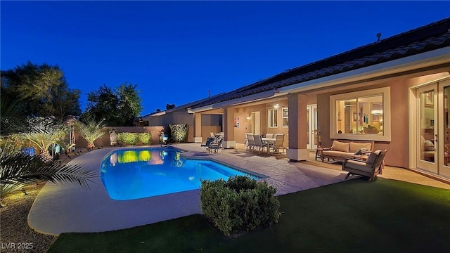 pool at twilight featuring a patio area, an outdoor living space, and a fenced backyard