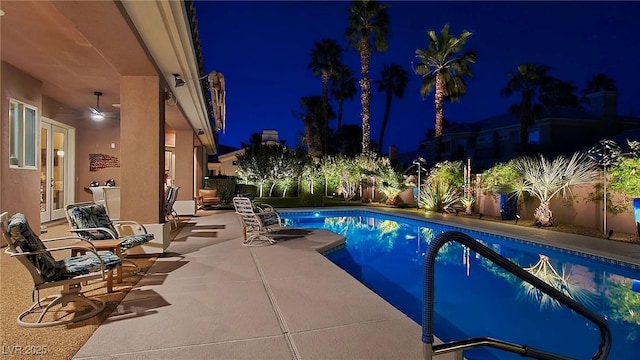 pool at twilight with french doors and a patio