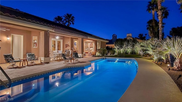 pool at twilight with a patio area and an outdoor pool