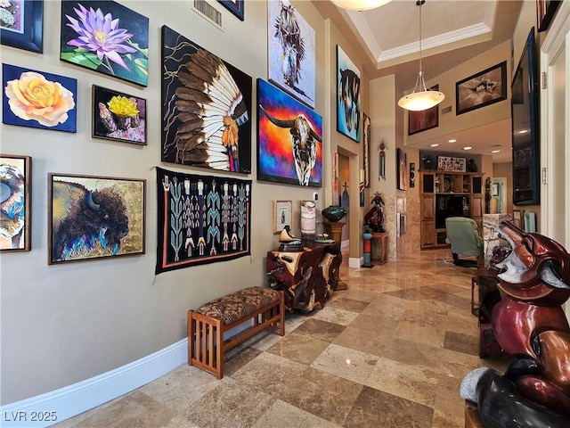 hallway featuring a high ceiling, crown molding, and baseboards