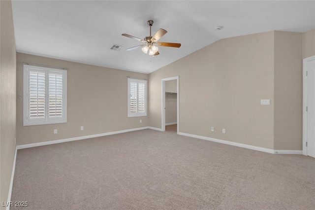 empty room featuring baseboards, a ceiling fan, visible vents, lofted ceiling, and light colored carpet