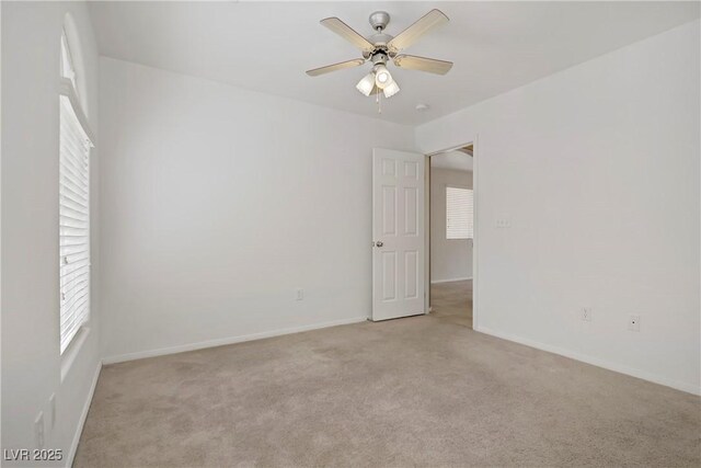 unfurnished room with baseboards, a wealth of natural light, and light carpet