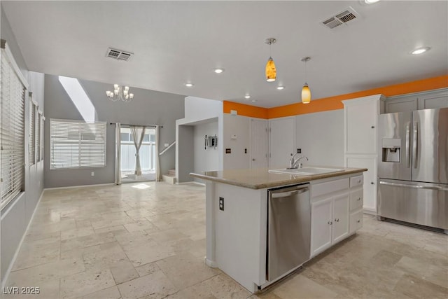 kitchen with appliances with stainless steel finishes, a sink, open floor plan, baseboards, and visible vents