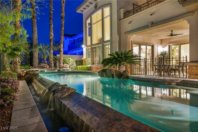 pool at twilight with a patio area, a ceiling fan, an infinity pool, and french doors