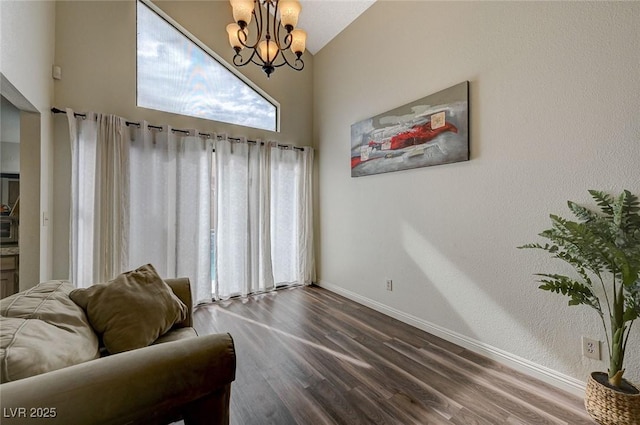 sitting room featuring dark wood-style flooring, baseboards, a chandelier, and lofted ceiling