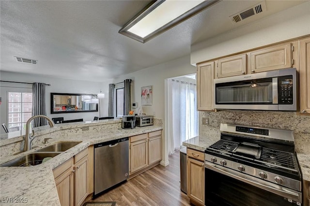 kitchen featuring stainless steel appliances, visible vents, a sink, and light brown cabinetry