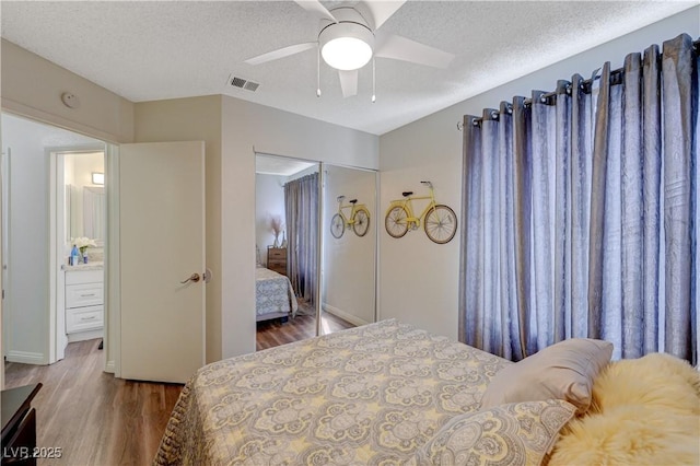 bedroom with visible vents, a textured ceiling, and wood finished floors