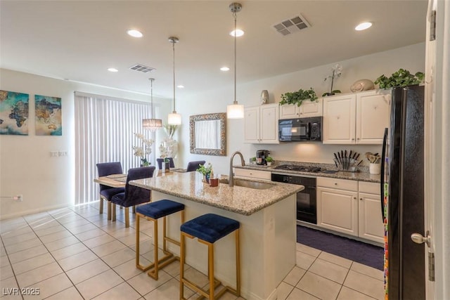 kitchen with light tile patterned floors, white cabinetry, black appliances, visible vents, and a sink