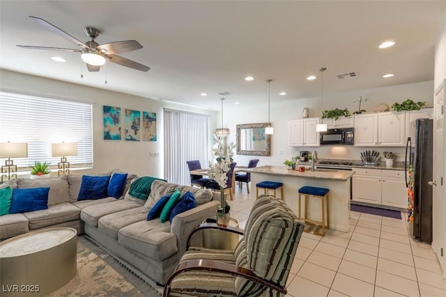 living room featuring light tile patterned floors, ceiling fan, visible vents, and recessed lighting
