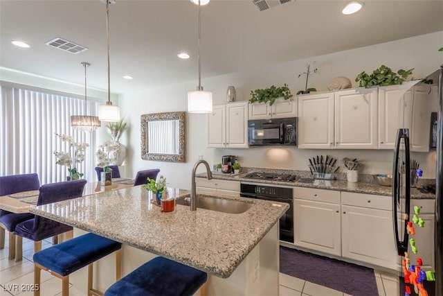 kitchen with light tile patterned floors, white cabinetry, black appliances, visible vents, and a sink