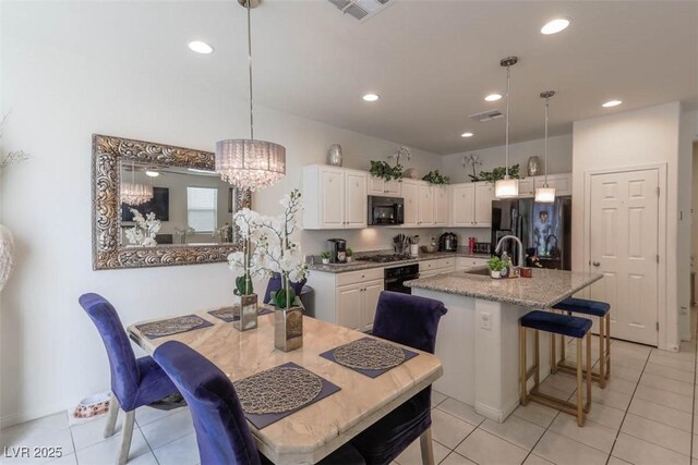 kitchen featuring a sink, visible vents, white cabinets, and black appliances