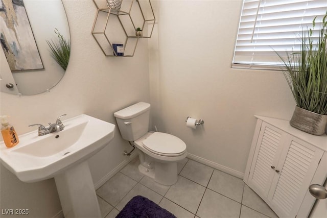 half bath featuring tile patterned flooring, baseboards, and toilet