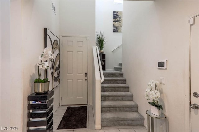 foyer entrance featuring visible vents, light tile patterned flooring, and stairs