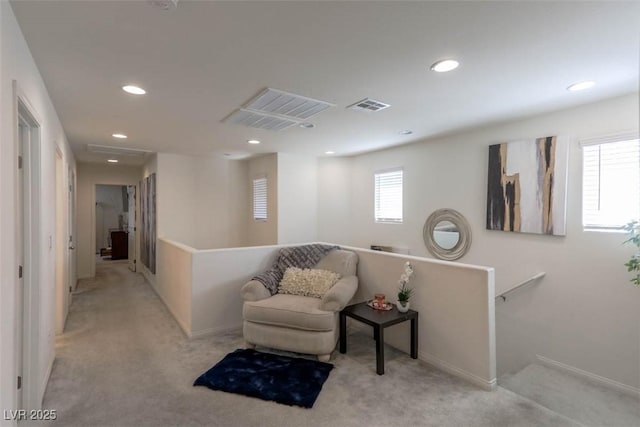 living area featuring light carpet, an upstairs landing, and visible vents