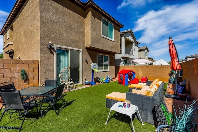 back of property with stucco siding, a fenced backyard, a lawn, and outdoor lounge area