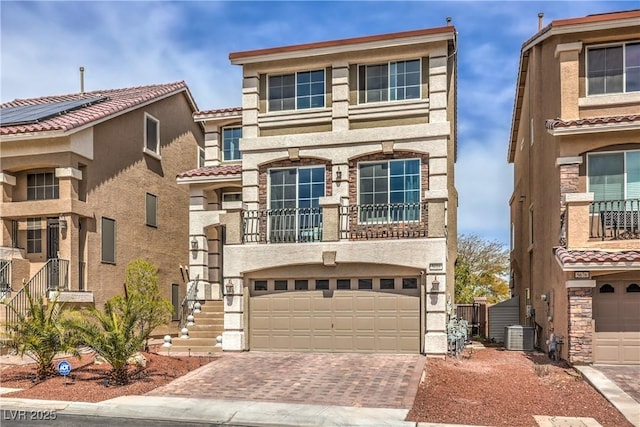 view of front facade with central air condition unit, stucco siding, decorative driveway, a tile roof, and an attached garage