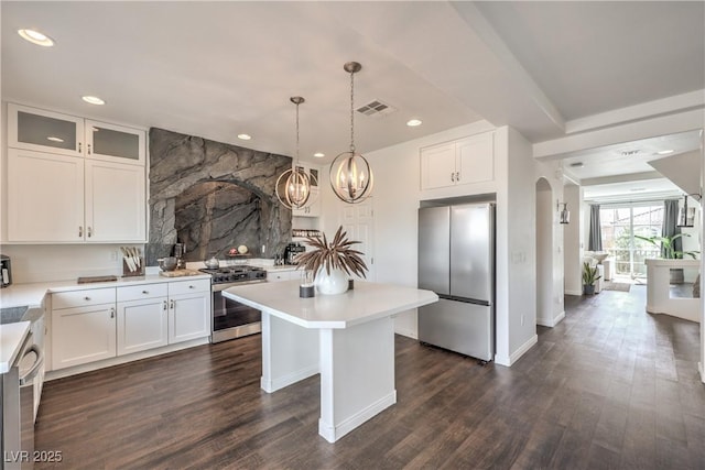 kitchen featuring visible vents, a center island, arched walkways, light countertops, and stainless steel appliances