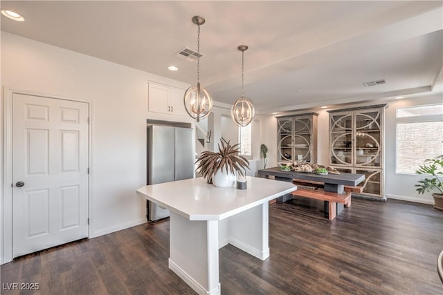 kitchen with freestanding refrigerator, dark wood finished floors, visible vents, a center island, and a notable chandelier