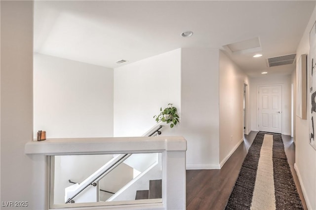 corridor featuring visible vents, baseboards, an upstairs landing, attic access, and wood finished floors