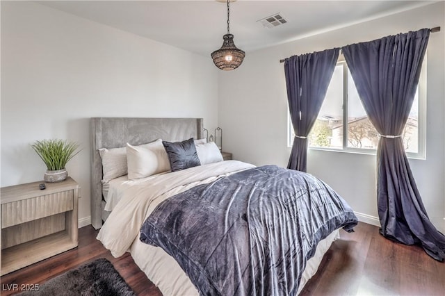 bedroom with visible vents, baseboards, and wood finished floors