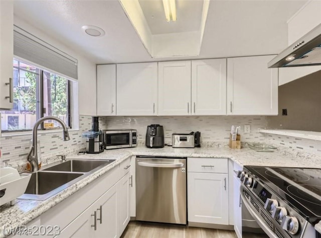kitchen featuring stainless steel appliances, a sink, white cabinets, tasteful backsplash, and extractor fan
