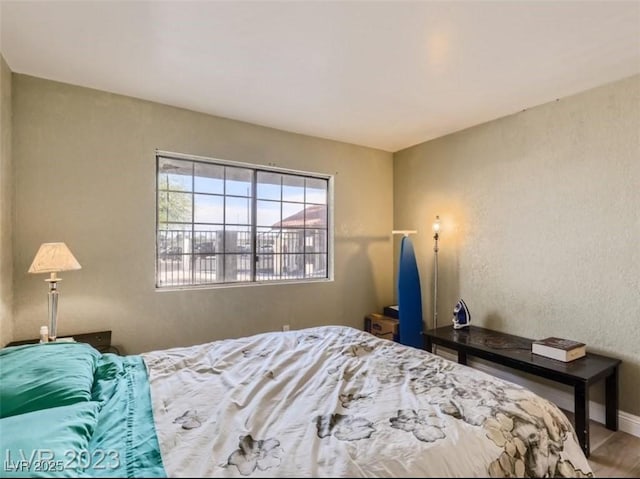 bedroom with wood finished floors, baseboards, and a textured wall