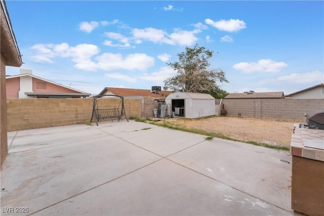 view of patio with an outbuilding, a fenced backyard, and a shed