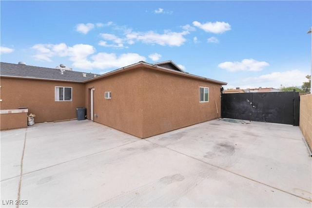 rear view of property with a patio area, stucco siding, and fence