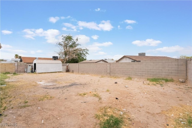 view of yard with a fenced backyard, an outdoor structure, and a storage unit