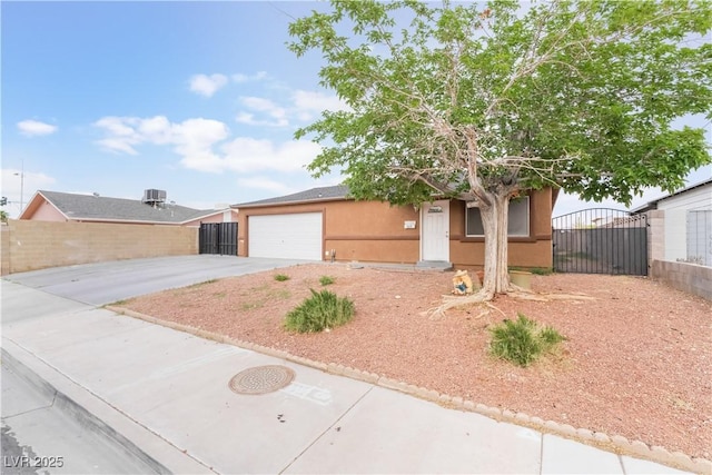 view of front of property with driveway, stucco siding, fence, and a gate