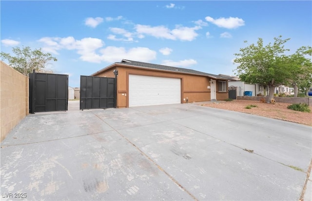 view of front of property featuring an attached garage, fence, stucco siding, a gate, and driveway