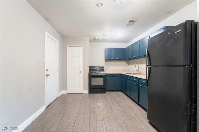 kitchen featuring visible vents, a sink, freestanding refrigerator, gas stove, and blue cabinetry