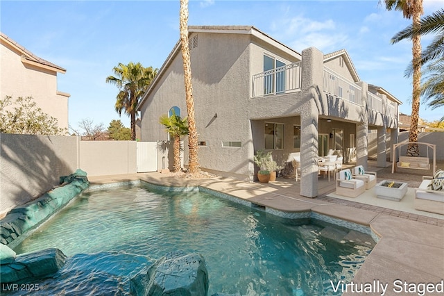 rear view of property featuring a patio, a balcony, stucco siding, a fenced backyard, and an outdoor hangout area