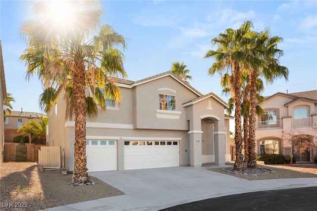view of front of home with a garage, driveway, stucco siding, and a gate