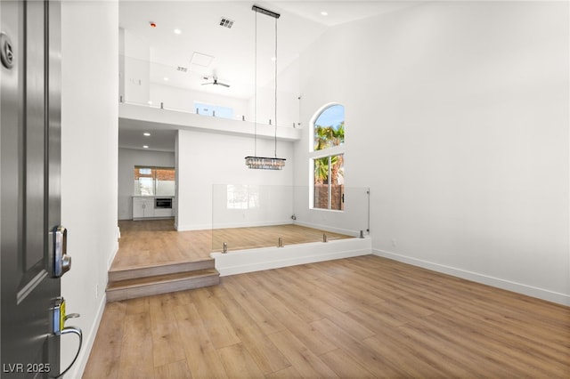 foyer entrance with visible vents, baseboards, high vaulted ceiling, and wood finished floors