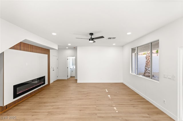 unfurnished living room with light wood-style flooring, a ceiling fan, visible vents, a glass covered fireplace, and recessed lighting