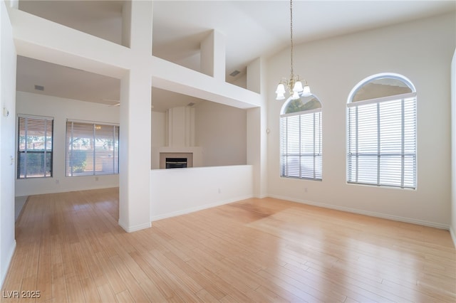 4176 Skywalker Ave, Las Vegas, NV 89120 - unfurnished living room with a chandelier, a fireplace, a high ceiling, light wood finished floors, and baseboards