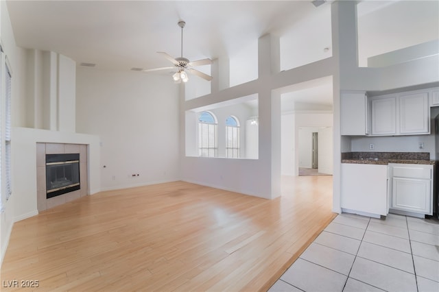 4176 Skywalker Ave, Las Vegas, NV 89120 - unfurnished living room featuring light wood finished floors, ceiling fan, a fireplace, a high ceiling, and baseboards