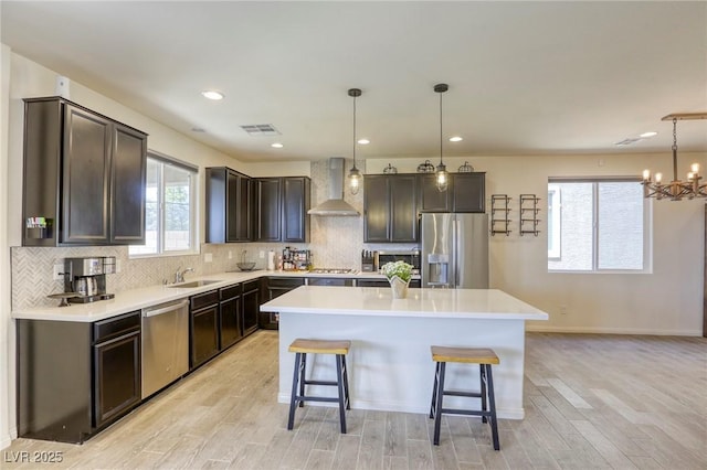 7445 Tinley Creek Ave, Las Vegas, NV 89113 - kitchen featuring a sink, wall chimney range hood, stainless steel appliances, a kitchen island, and a breakfast bar area