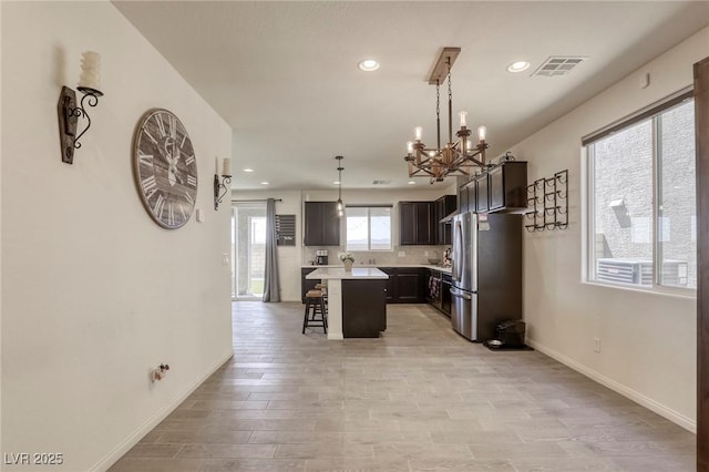 7445 Tinley Creek Ave, Las Vegas, NV 89113 - kitchen featuring an inviting chandelier, recessed lighting, light countertops, freestanding refrigerator, and a breakfast bar area