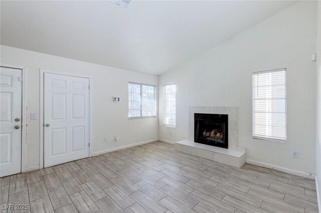 4732 Krissylouise Way, Las Vegas, NV 89121 - unfurnished living room featuring a high end fireplace, wood finish floors, vaulted ceiling, and baseboards