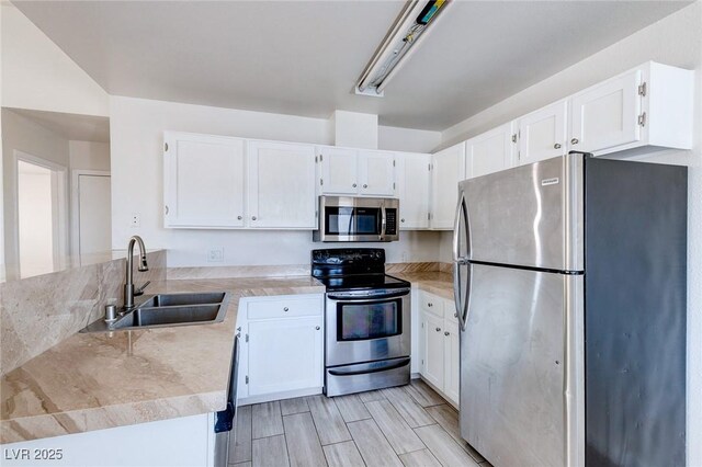 4732 Krissylouise Way, Las Vegas, NV 89121 - kitchen featuring wood finish floors, a peninsula, white cabinetry, appliances with stainless steel finishes, and a sink